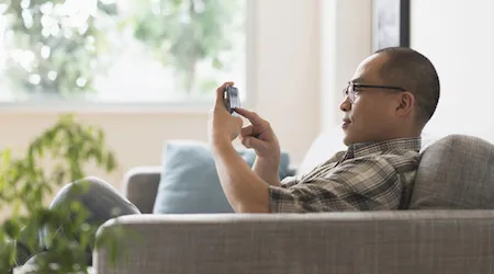 Asian man using a cell phone on sofa