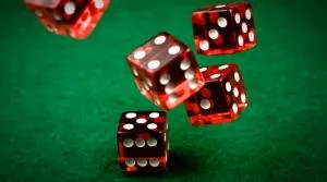 Red dice rolling on a green table.