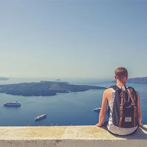 A person with backpack sitting down and looking at a view