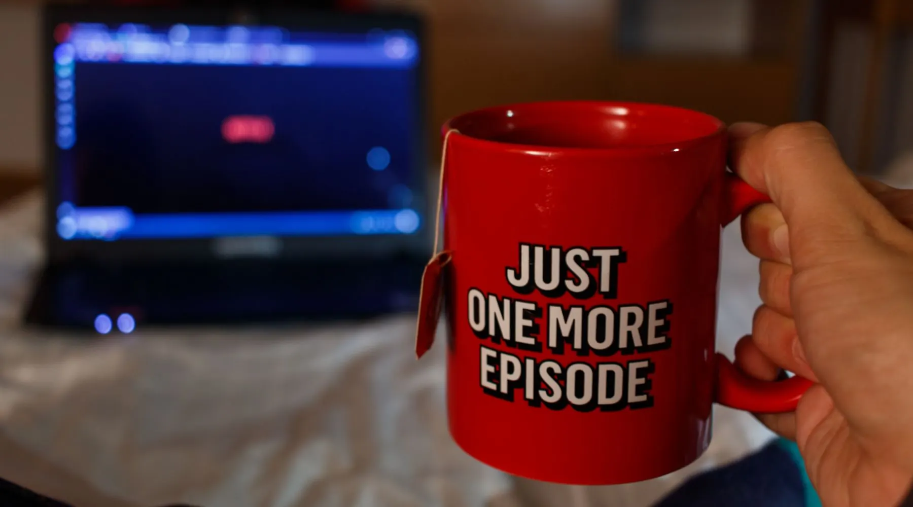 Man Watching series while holding with a cup of tea with streaming inspired inscription. Just one more episode.