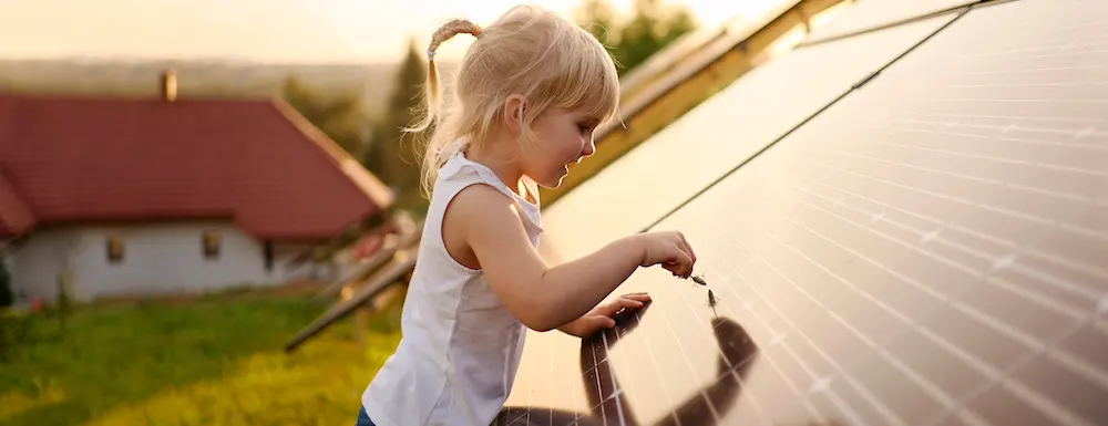 Little blonde girl pointing at solar panels