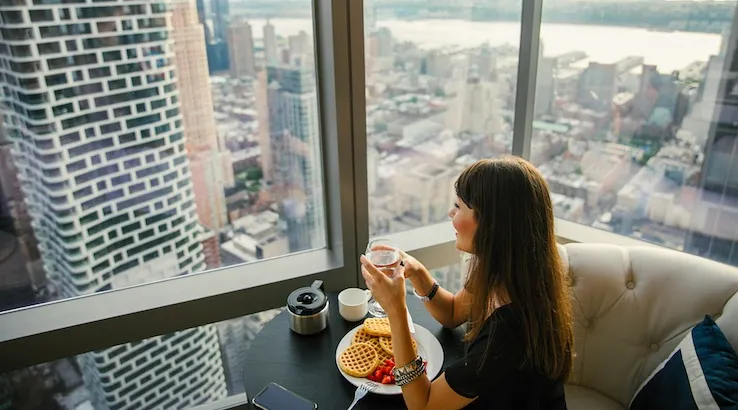 Girl eating breakfast in hotel with city view