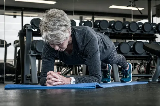 Strong women: senior woman gym workout floor exercises - yoga plank position