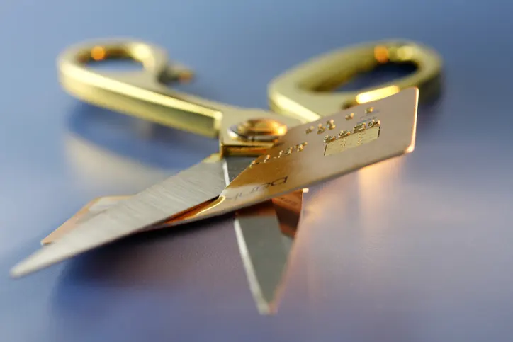 Gold scissors cutting up a gold credit card