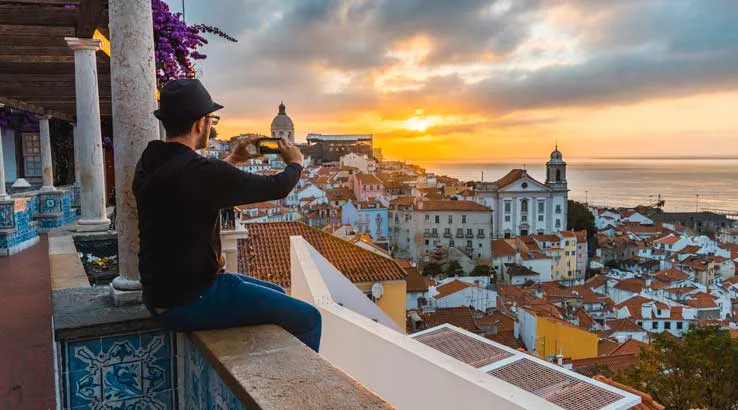 Tourist photographing with smartphone at sunrise in Lisbon, Portugal