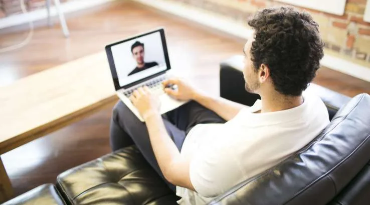 Man sitting on couch using laptop for video meeting