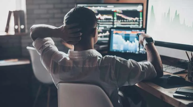 Man sitting at computer looking at trading charts. 