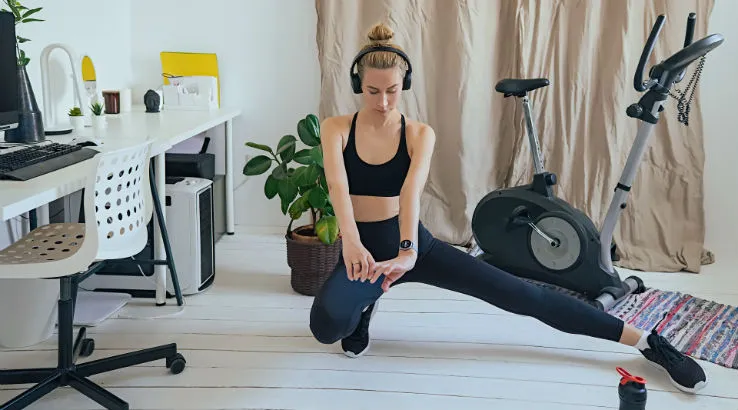 Woman stretching at home with exercise bike in the background