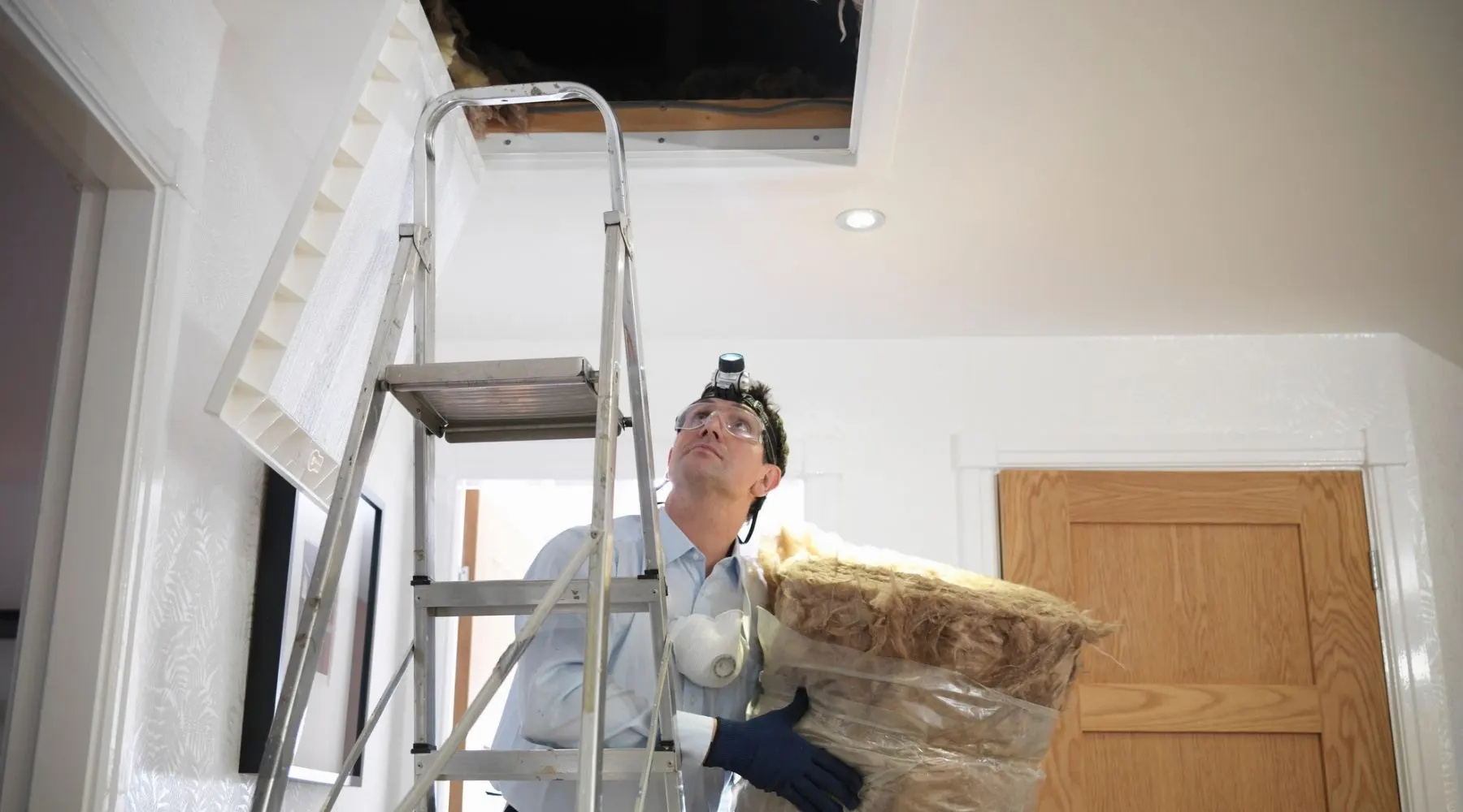 A man installs insulated batting in an attic.