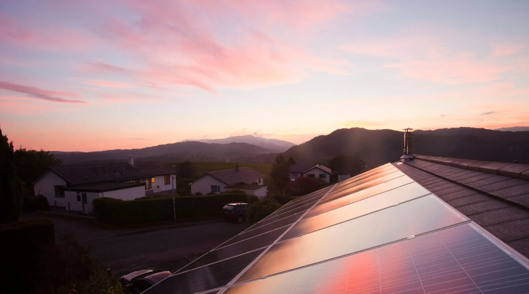 The sun sets over residential rooftop solar panels.