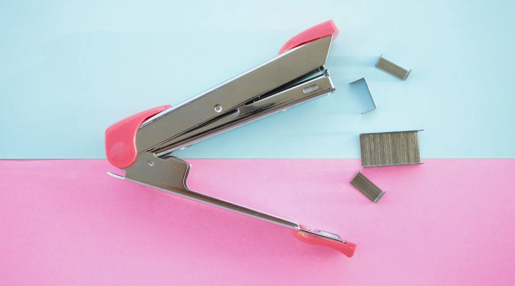 A stapler on a blue and pink background.