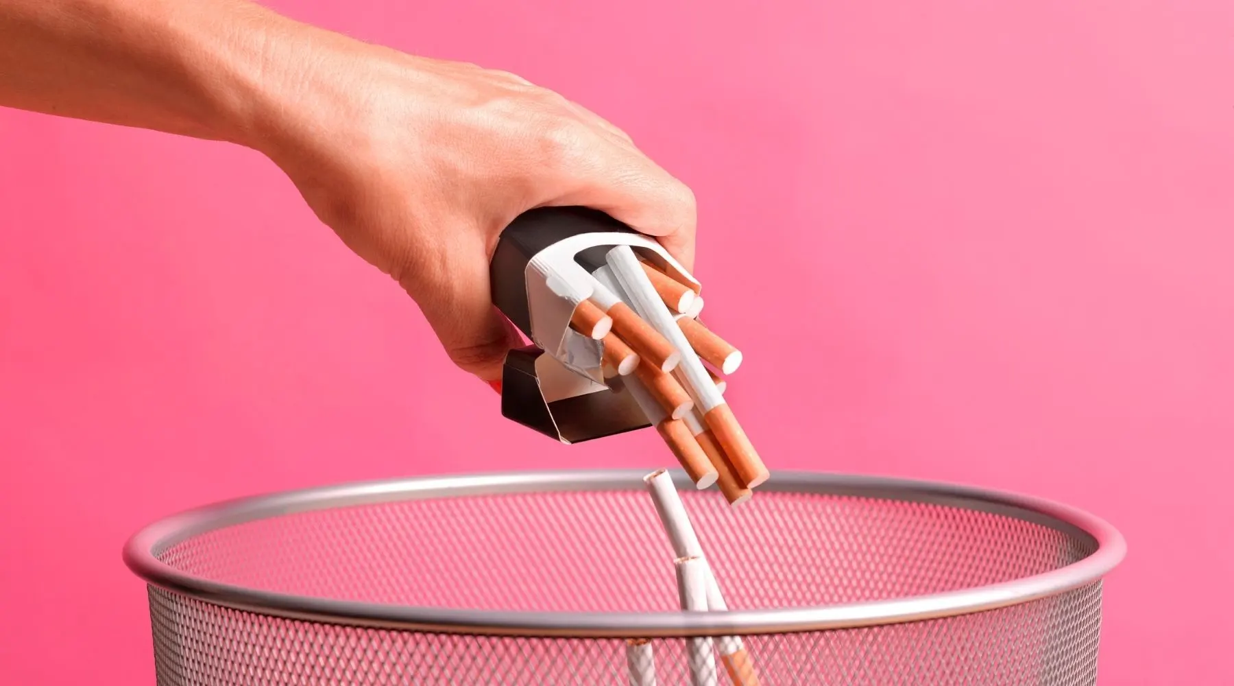 A mans hand is shown tipping cigarettes out of the packet and into a bin.