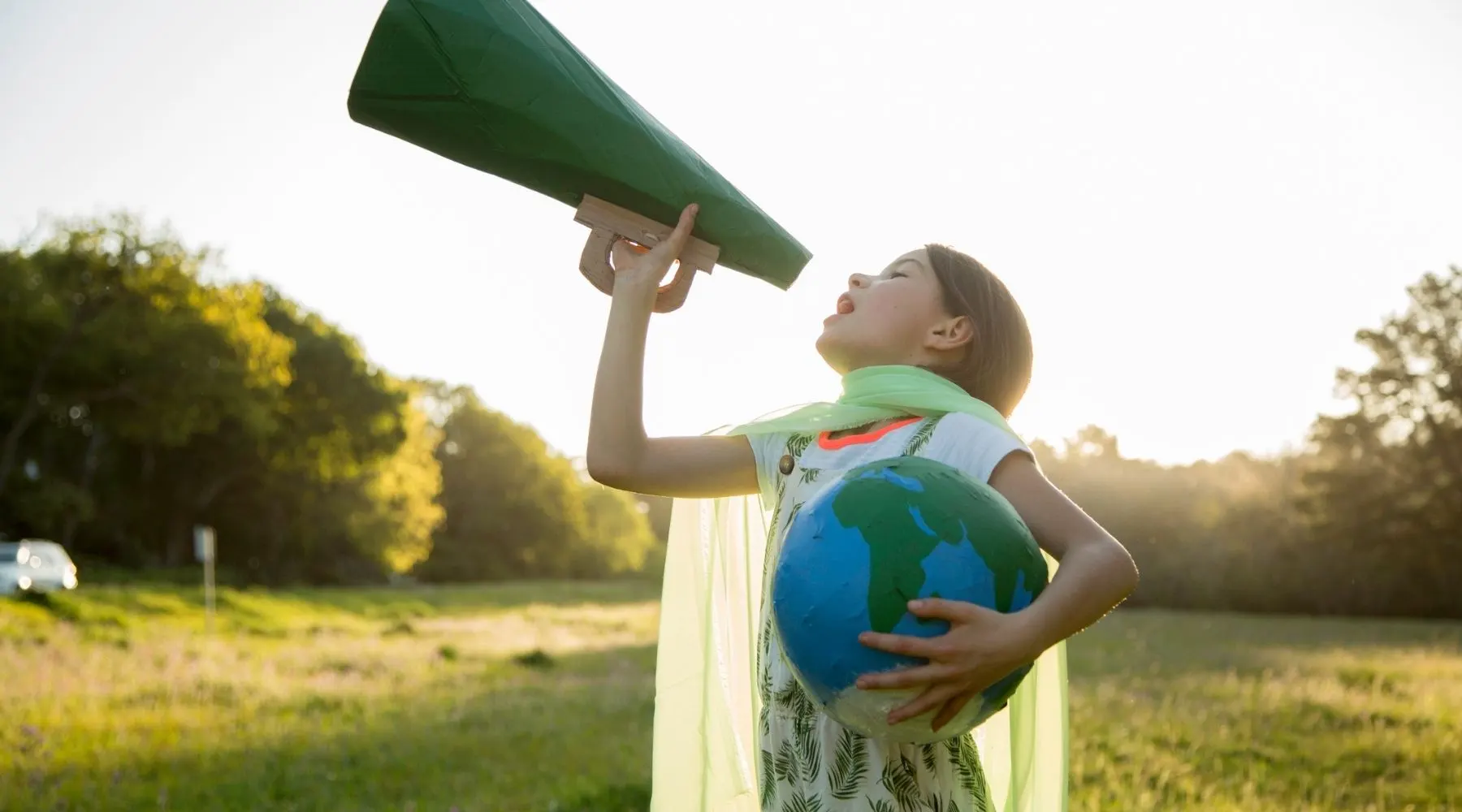 A young girl shouts into a megaphone while holding a papier-mache earth.