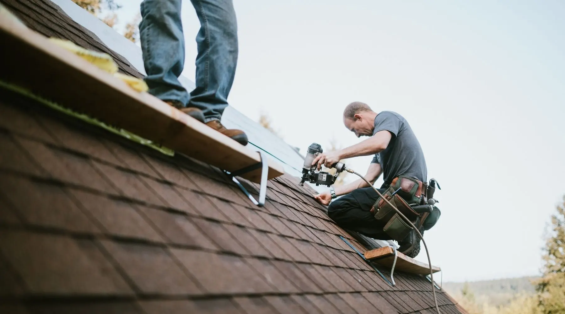 Two men work on fixing a roof together.