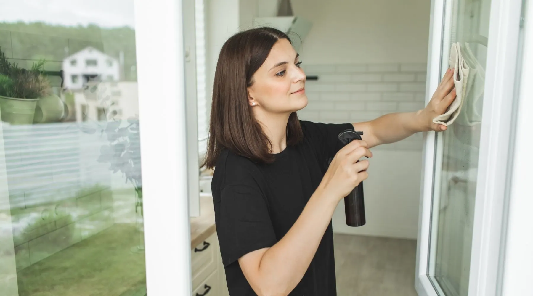 A young woman cleans her window using natural products.