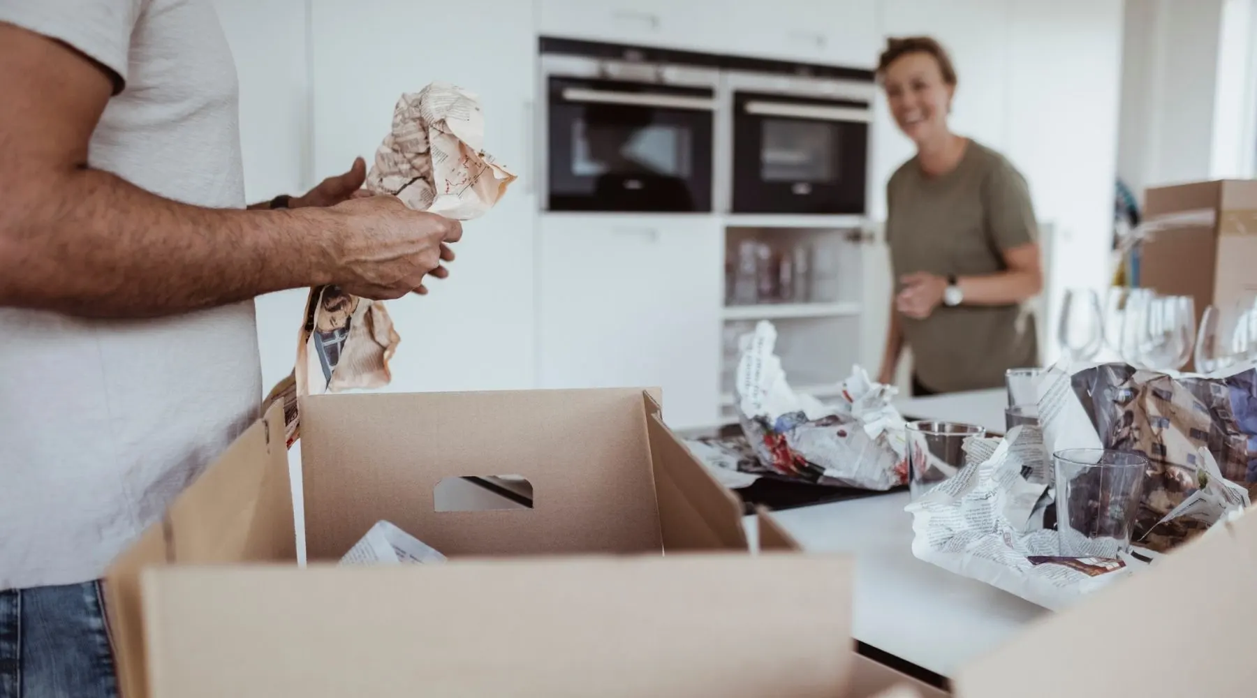 Midsection of male unpacking cardboard box while smiling female standing in new house