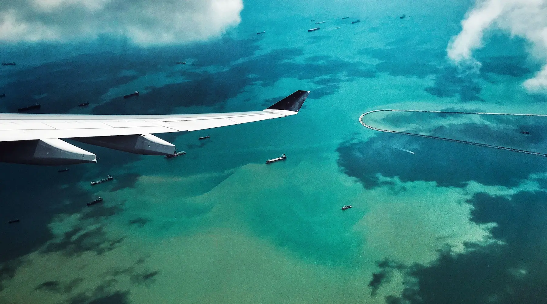 An aerial view of Fiji, with a plane's wing showing as it flies across the islands.
