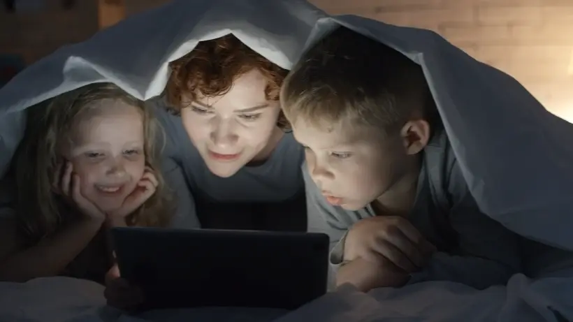 A woman and 2 kids looking at a tablet