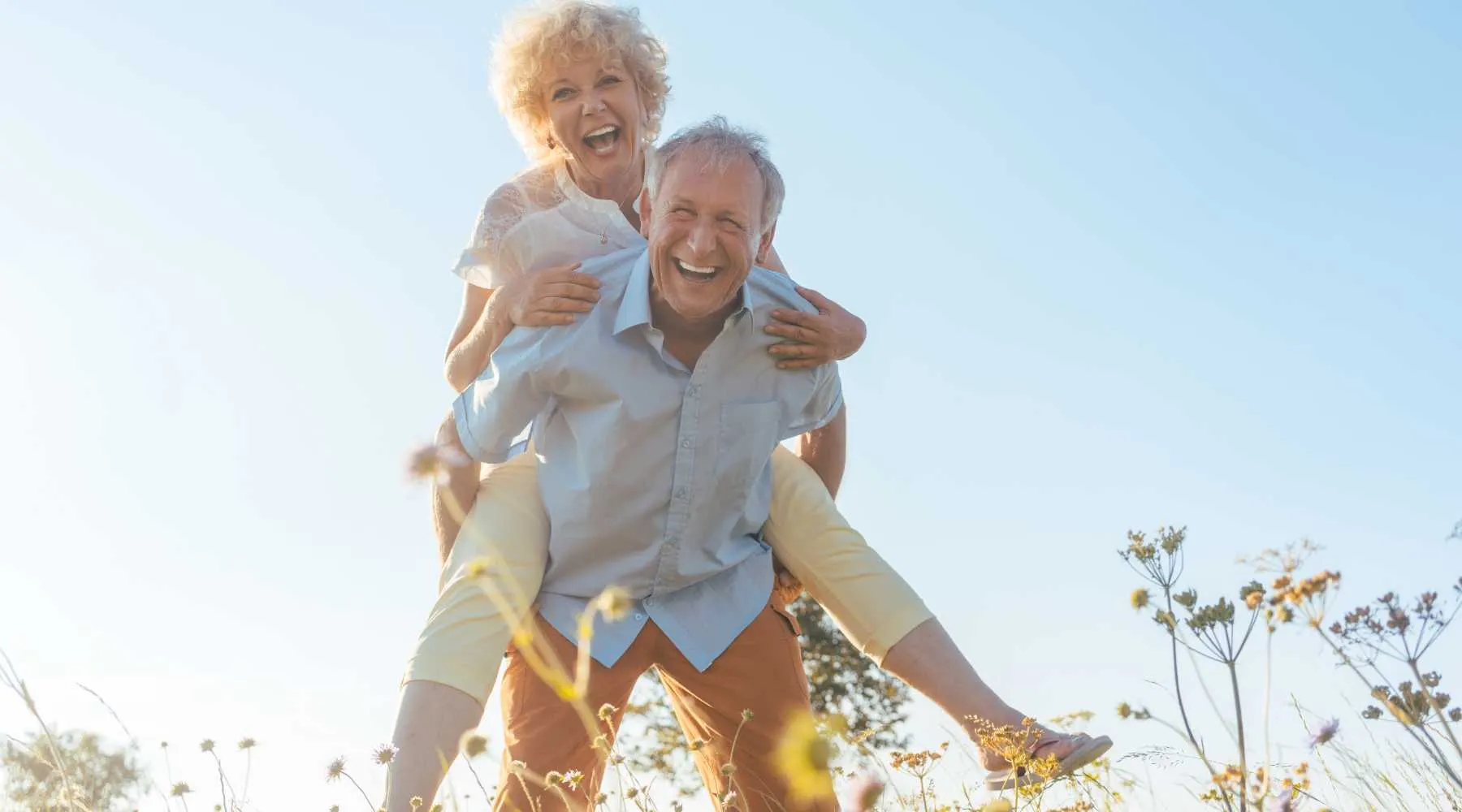 An older couple laughing in a field