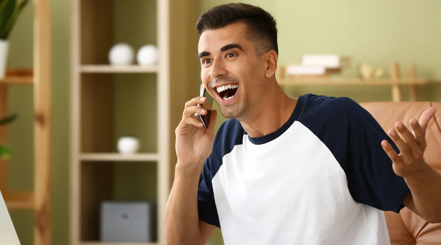 Happy Young Man Talking by Mobile Phone at Home