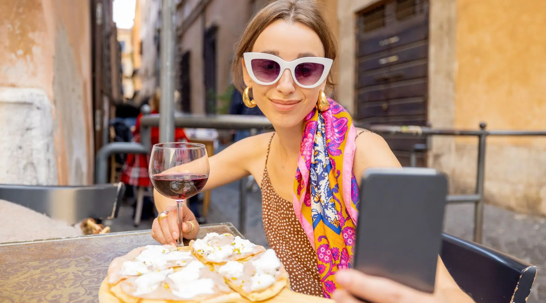 Woman on her phone while eating pizza in Italy