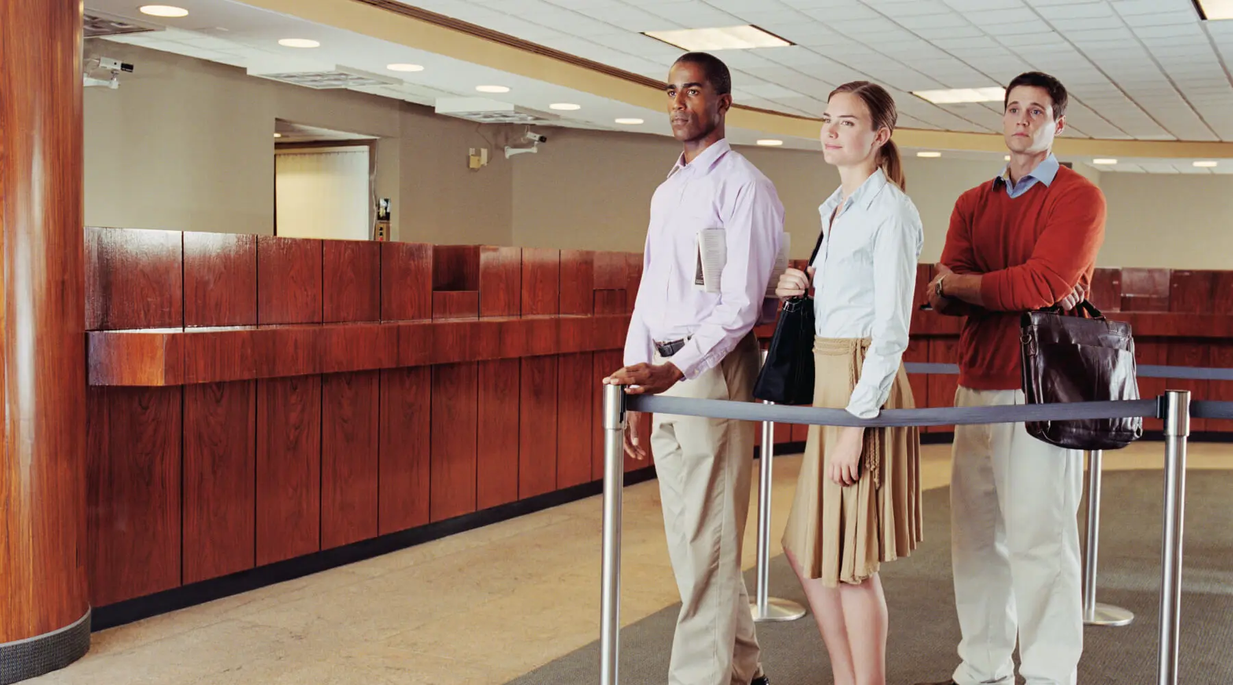 Two men and one woman in line at the bank